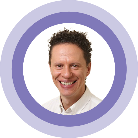 Smiling person with curly hair in a white shirt inside a purple circular frame
