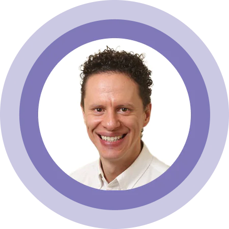 Smiling person with curly hair in a white shirt inside a purple circular frame