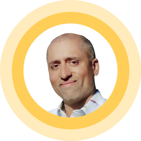 Bald man smiling, wearing a white shirt, inside a yellow circular frame on a white background.