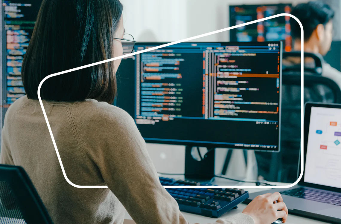 Woman coding on a computer screen in a modern office environment