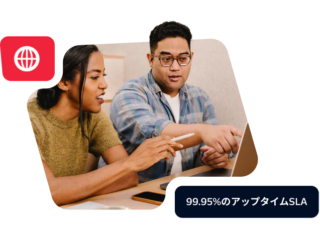 Two colleagues discussing work at a laptop showcasing a commitment to 99.95% uptime SLA