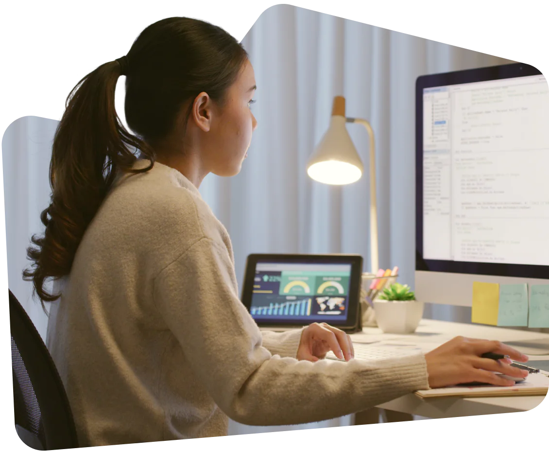 Person with dreadlocks typing on a laptop with code on the screen