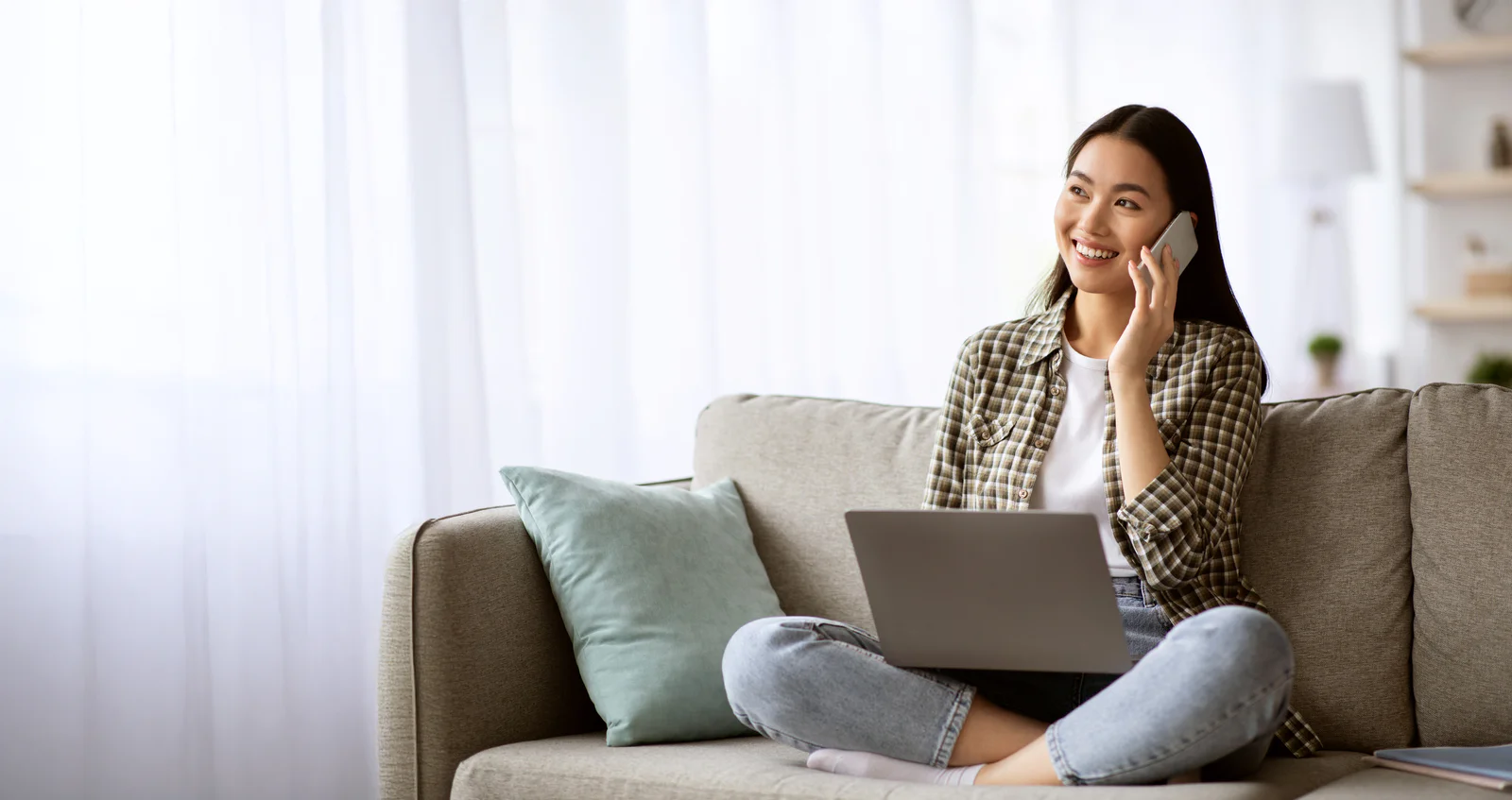 Portrait of smiling mid adult man with credit card using mobile phone and laptop on dining table at home