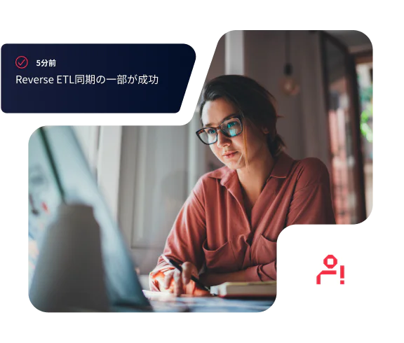 Woman wearing glasses and pink shirt working on a laptop with an ETL sync notification.