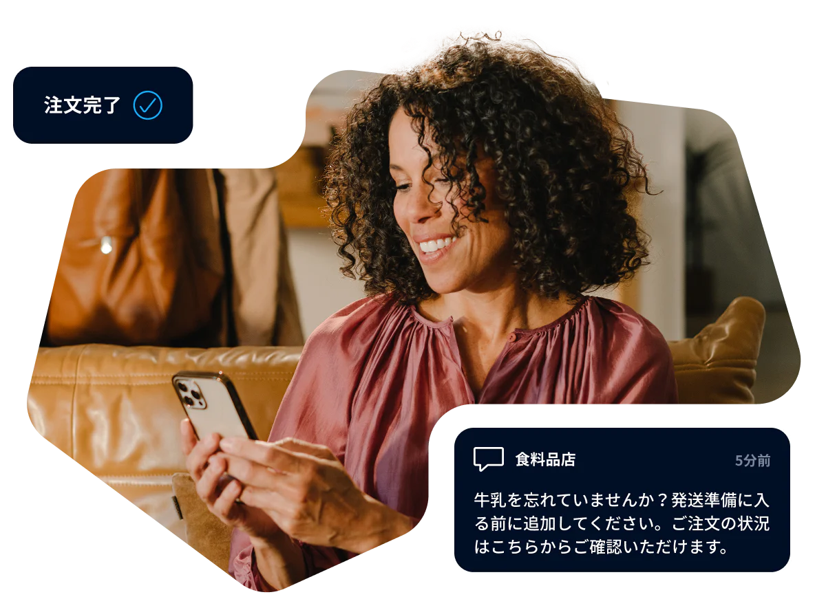 Woman smiling at her smartphone while receiving an online grocery order confirmation message.