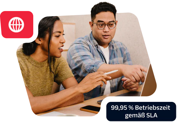 Two colleagues discussing work at a laptop showcasing a commitment to 99.95% uptime SLA