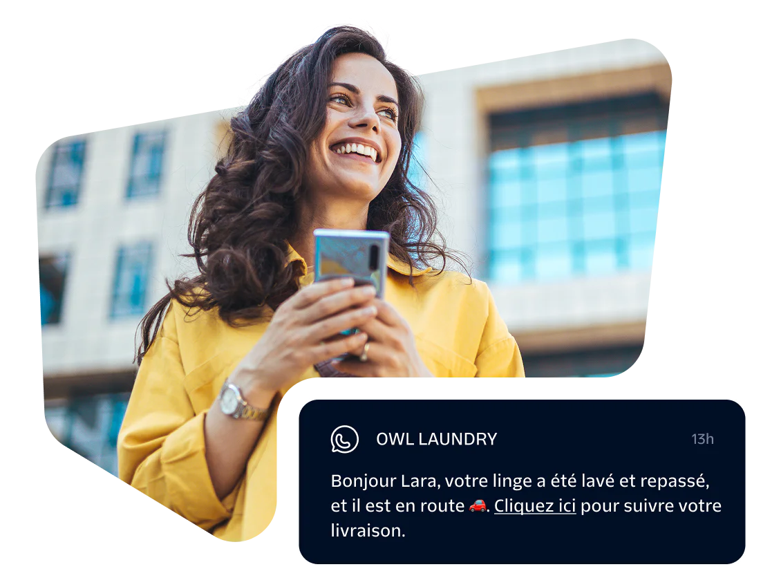 Smiling woman holding phone with a message notification from Owl Laundry.