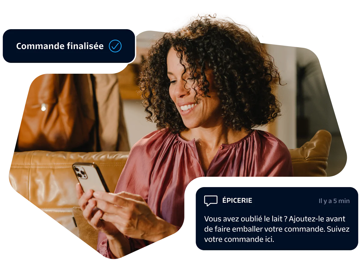 Woman smiling at her smartphone while receiving an online grocery order confirmation message.
