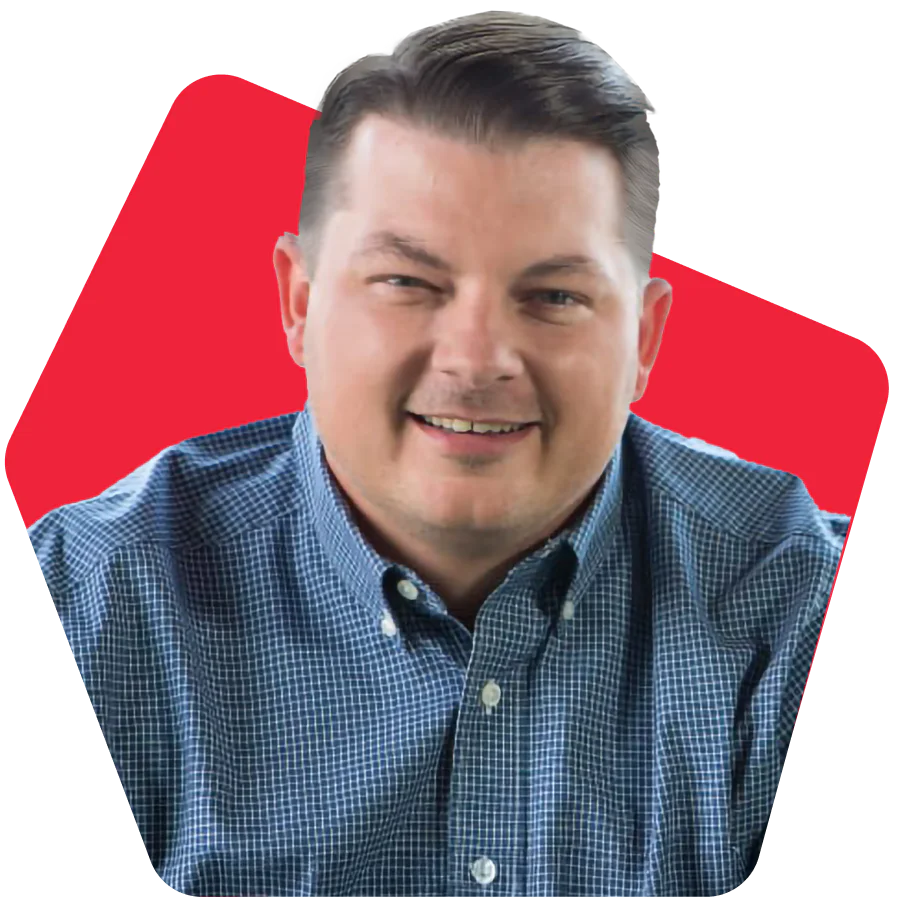 Man in a blue checkered shirt smiling with a red background.