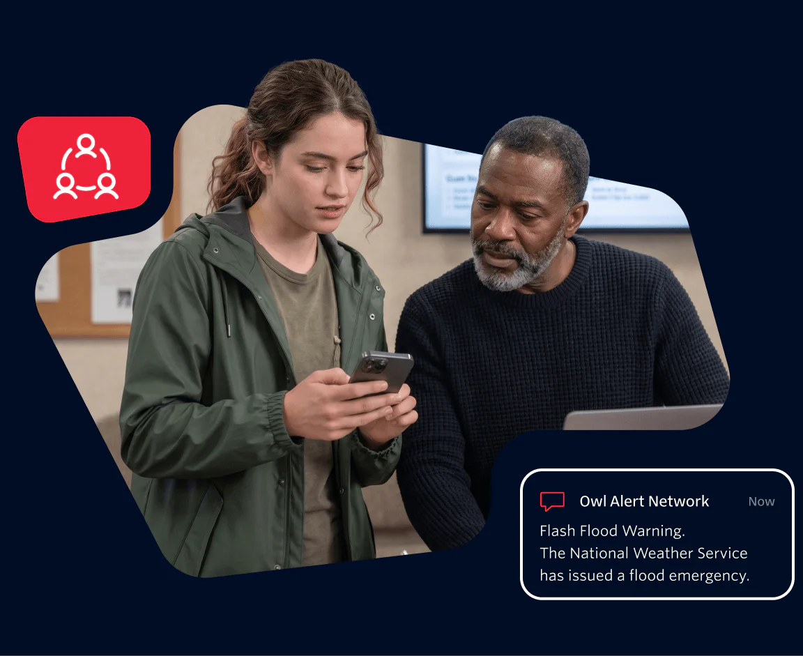Two people looking at a smartphone displaying a flash flood warning alert from Owl Alert Network.