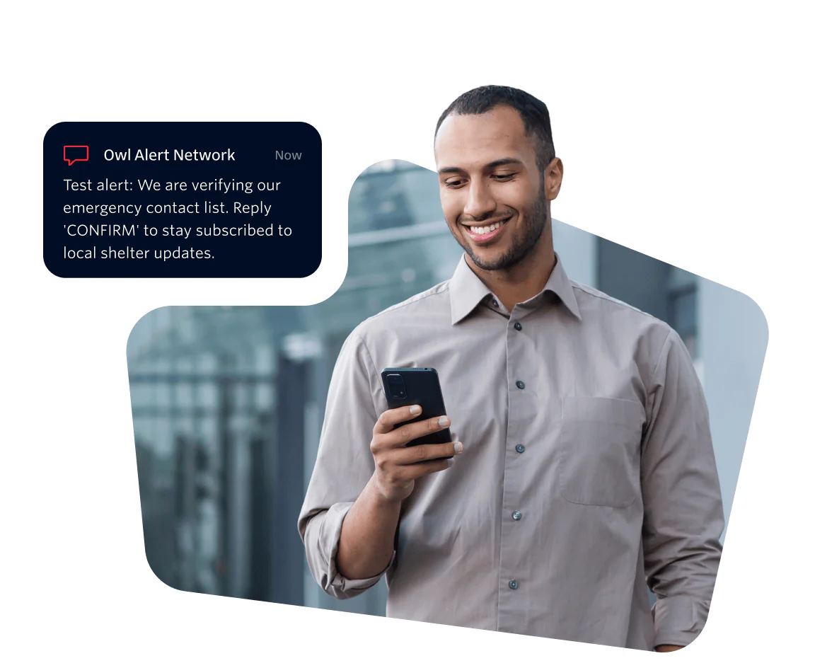 Man smiling and reading an alert message on his smartphone.