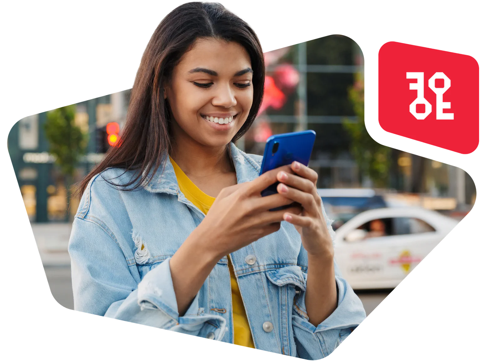 Woman in denim jacket smiling and looking at her smartphone on the street