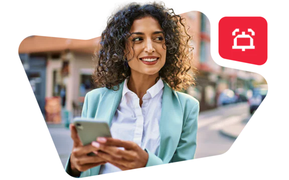 Woman in business attire holding a smartphone, smiling, with a red notification alert icon in the corner.