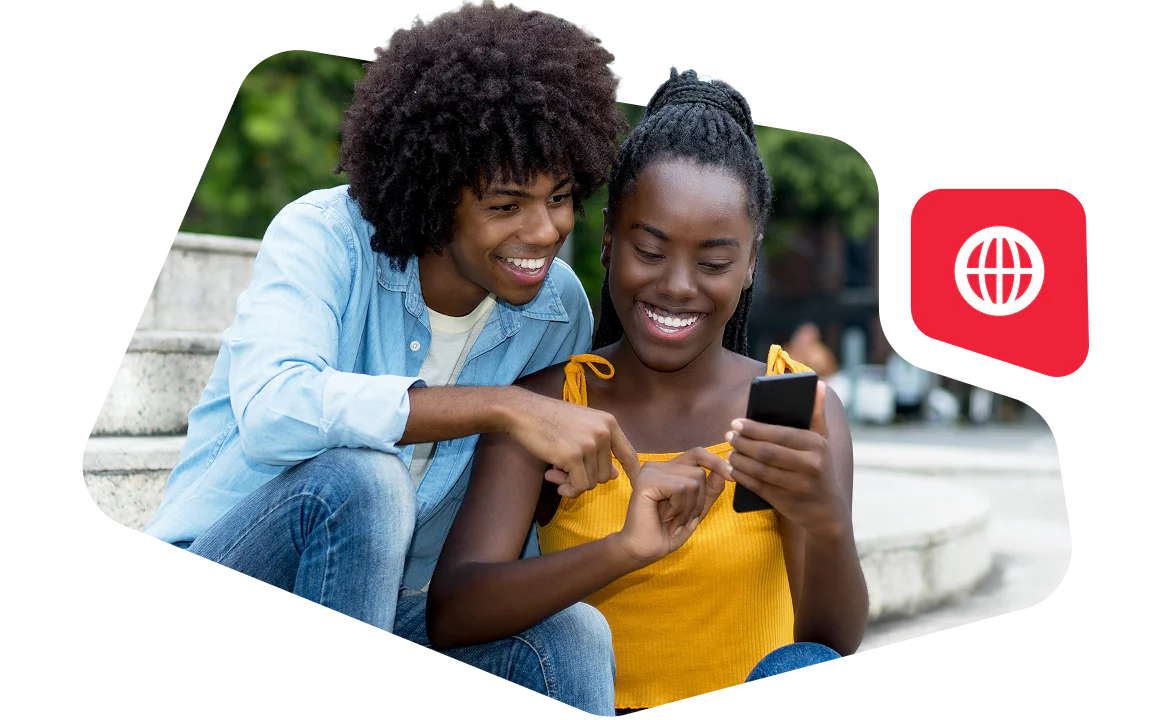 Smiling young couple sitting on steps, looking at a phone together.