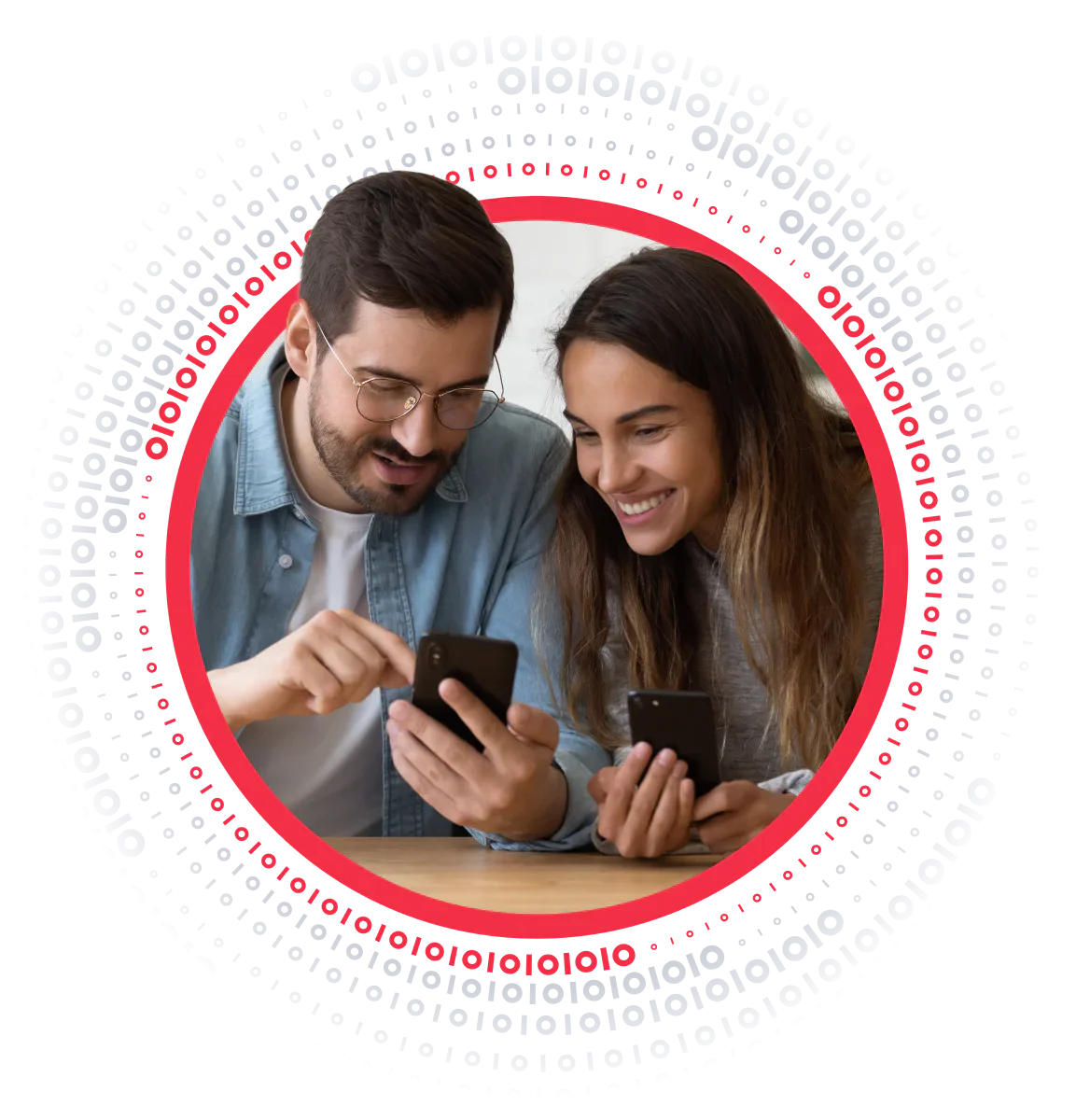 A man and woman smiling and looking at their smartphones, sitting at a table.