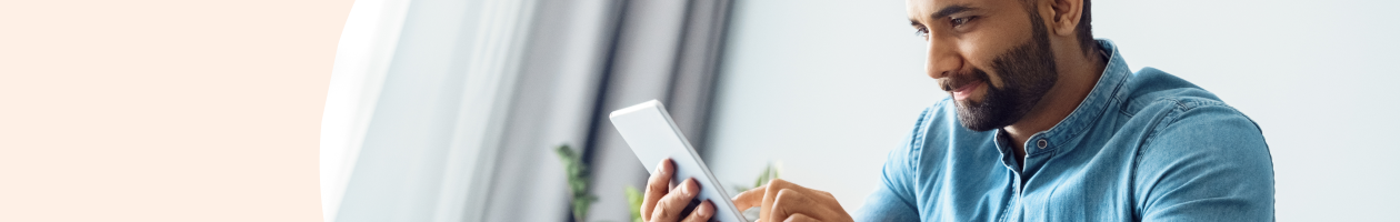 Man in blue shirt using a tablet device indoors