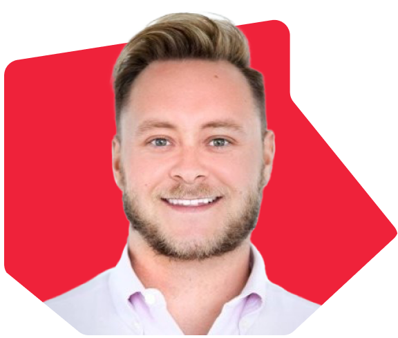 Man with short blond hair and beard wearing a white collared shirt, smiling against a red background.