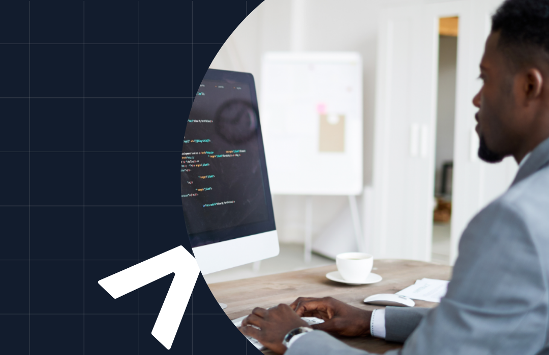 Man in suit working on coding on a computer at a desk with a coffee cup nearby