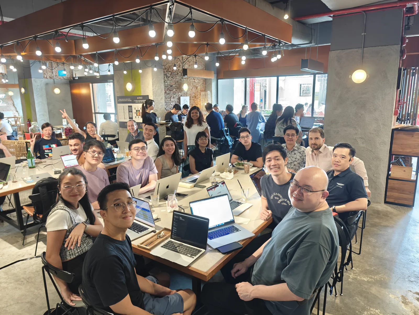 A group of people working together around tables with laptops in a modern office space.
