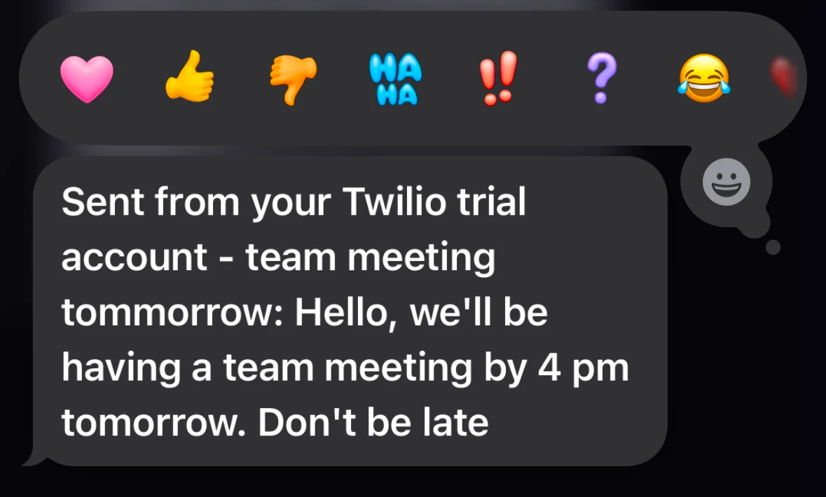 Text message about a team meeting from a Twilio trial account with various emoji reactions.