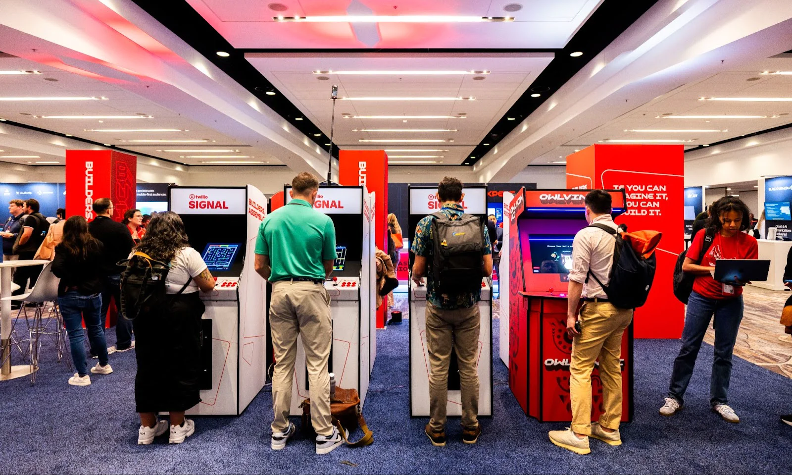 People interacting with tech displays in a convention center. People interacting with tech displays in a convention center.