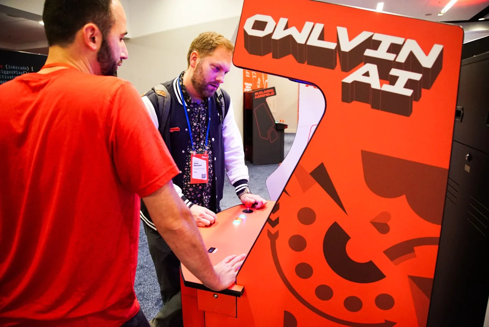 Two people playing an arcade game with OWL VIN AI on the machine at a tech event. Two people playing an arcade game with OWL VIN AI on the machine at a tech event.
