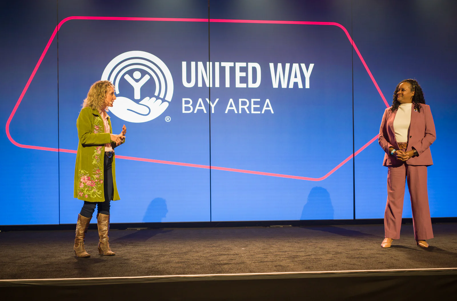 Two women stand on a stage in front of a United Way Bay Area sign.