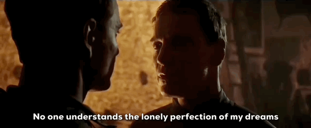 Two people face each other in a dimly lit scene with subtitles reading No one understands the lonely perfection of my dreams.