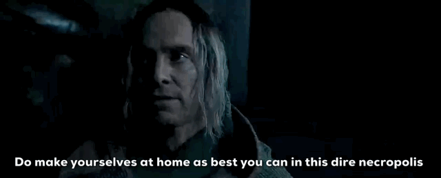 Man with long blonde hair says to make oneself at home in a dark and eerie setting