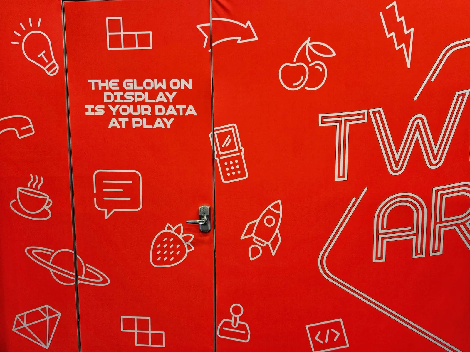 Red wall with white tech, fruit, and space icons and a message about data. Red wall with white tech, fruit, and space icons and a message about data.