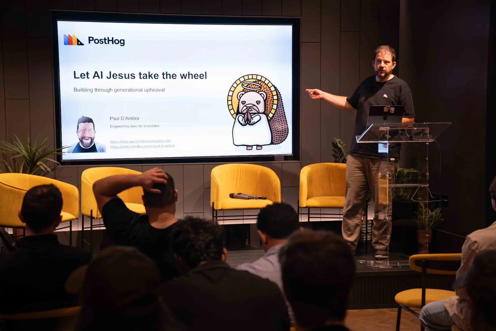 Man giving a presentation on AI with slides in the background at a tech event with audience seated.
