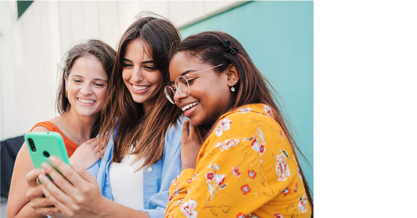 women smiling and looking at a phone together