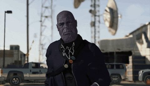 animated gif of Thanos pressing a button on his phone and causing an explosion behind him, which he&#x27;s walking away from.