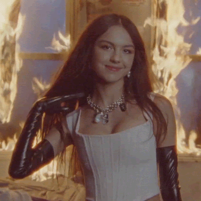 gif of Olivia Rodrigo standing with flames in the background from good 4 u music video