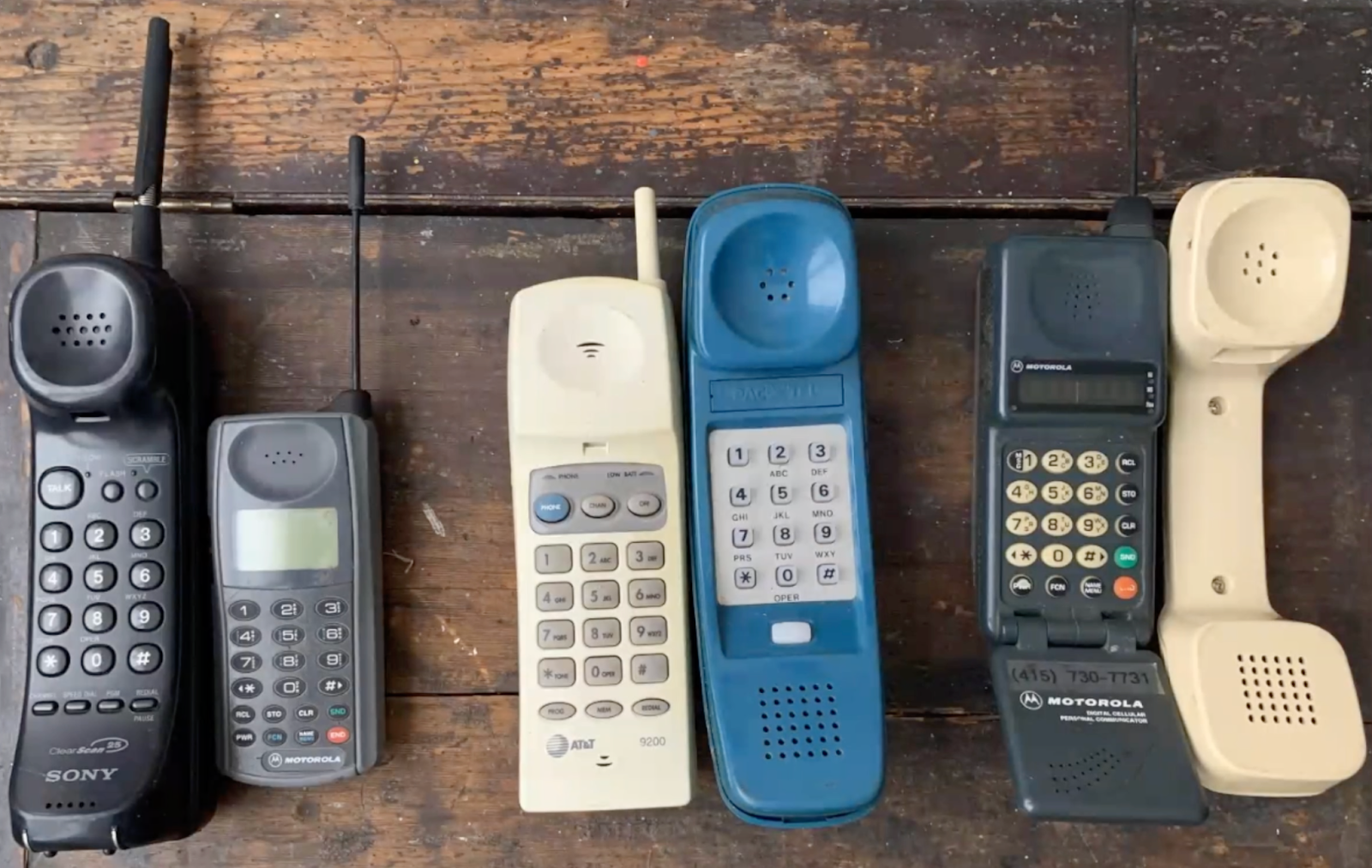 An image of phones through the years lined up, including cordless home telephones, motorola cell phones, and rotary phone receivers
