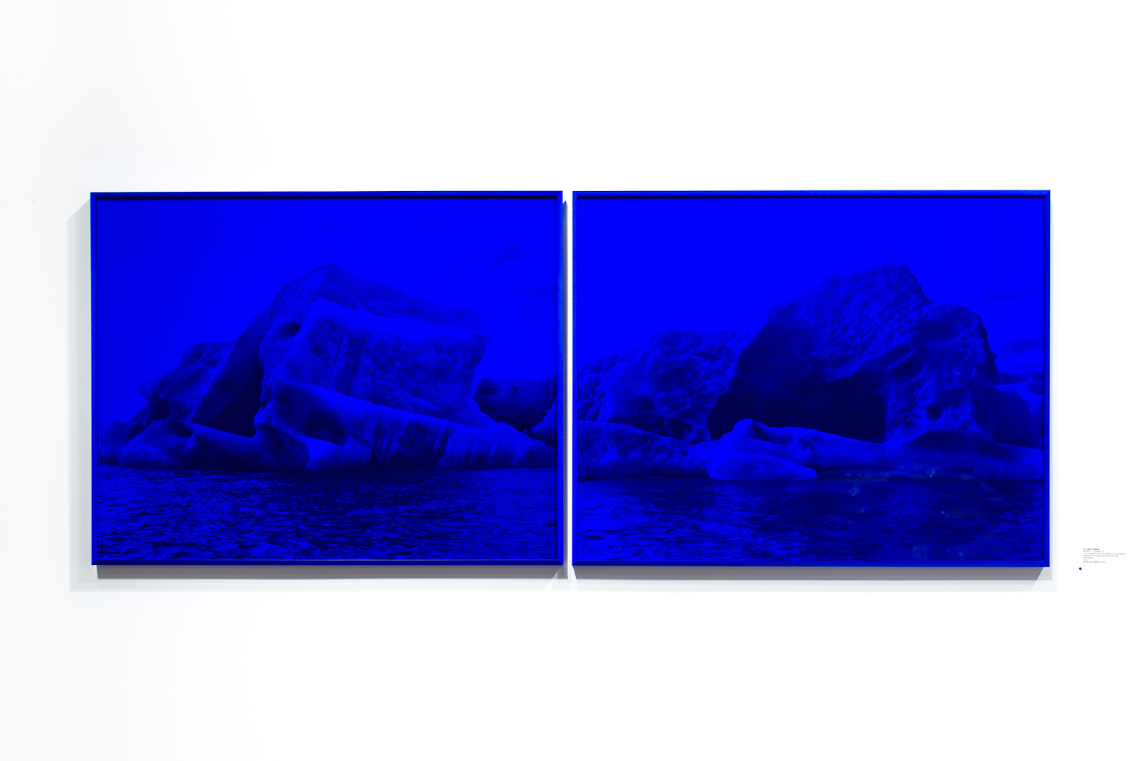 A photo of Justin Levesque&#x27;s art piece called Melt Down, which features two images of ice bergs in the Arctic overlayed with blue plexiglass.