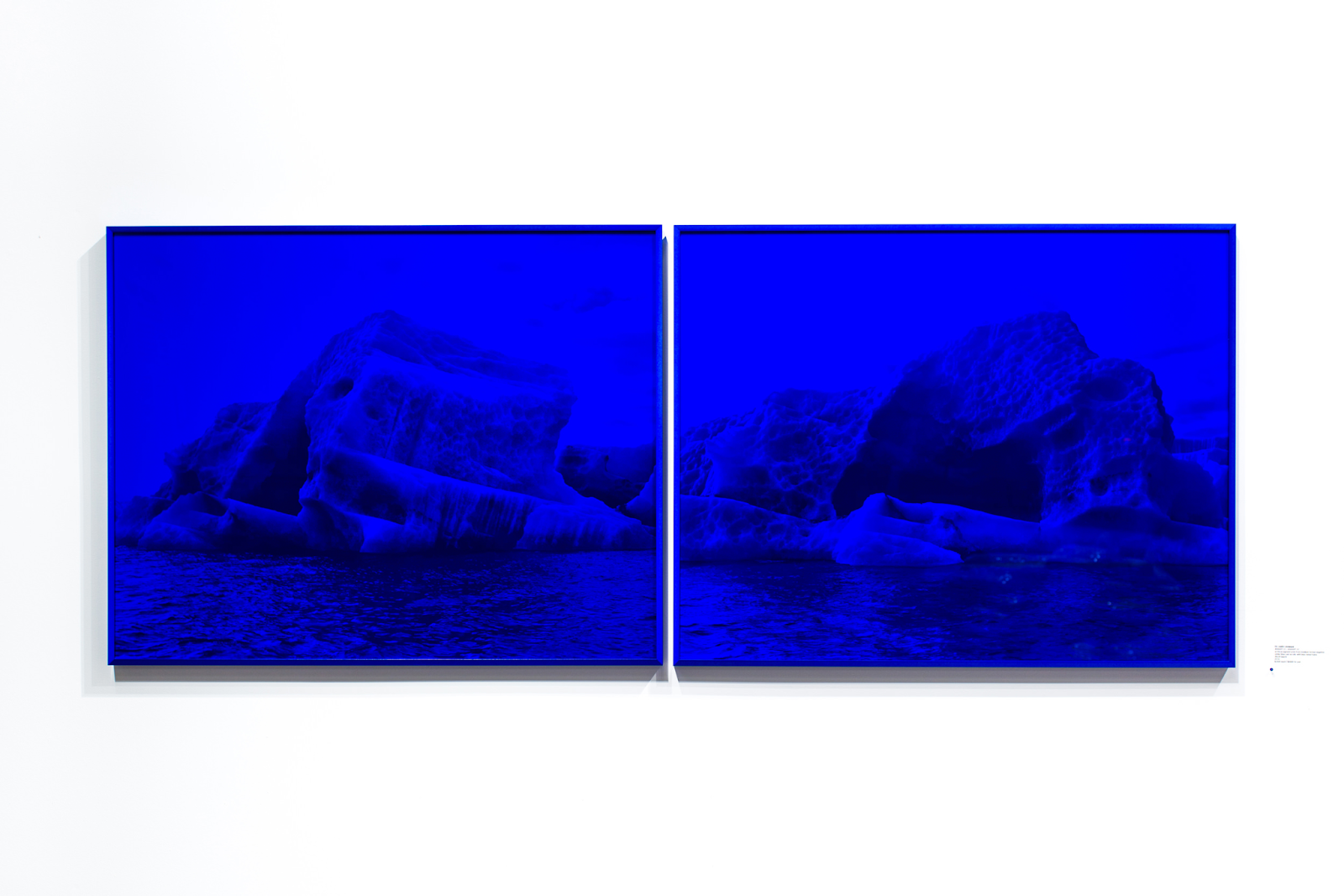 A photo of Justin Levesque's art piece called Melt Down, which features two images of ice bergs in the Arctic overlayed with blue plexiglass.