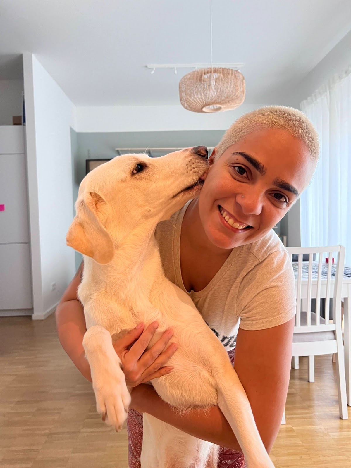 Me and my dog Tonino. I"m a black woman, with shaved and dyed hair, holding my dog while he licks my face