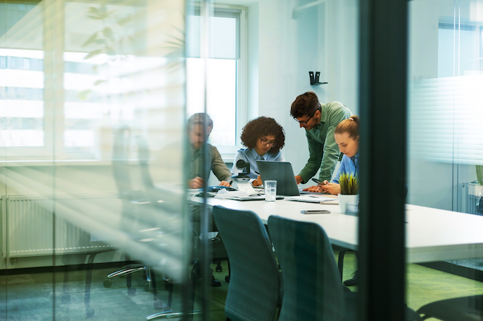 Four colleagues discussing data around a table in a modern office setting.