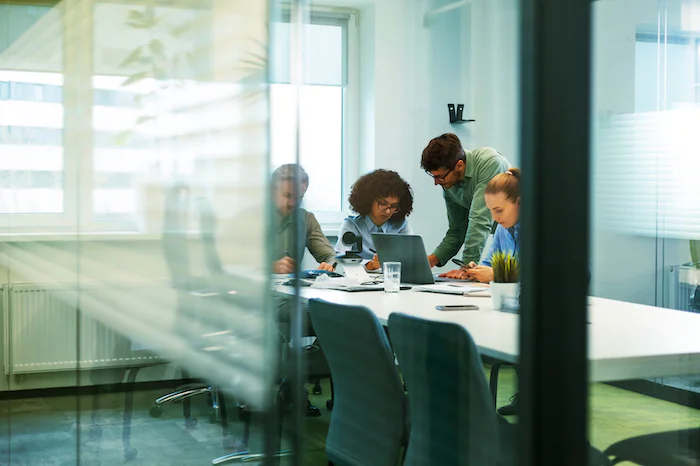 Four colleagues discussing data around a table in a modern office setting.