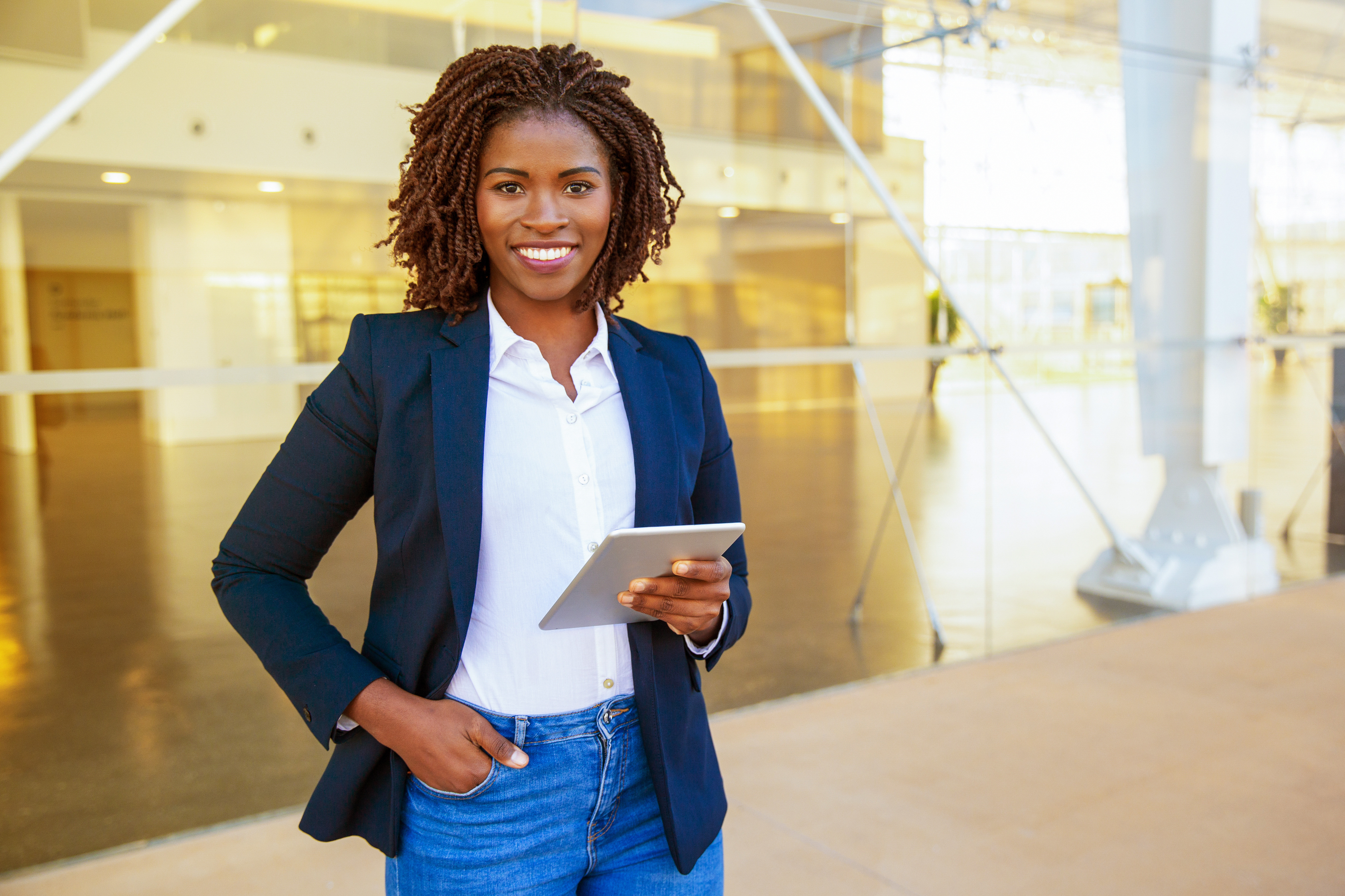 Businesswoman with tablet in hand standing in a bright, modern office environment.