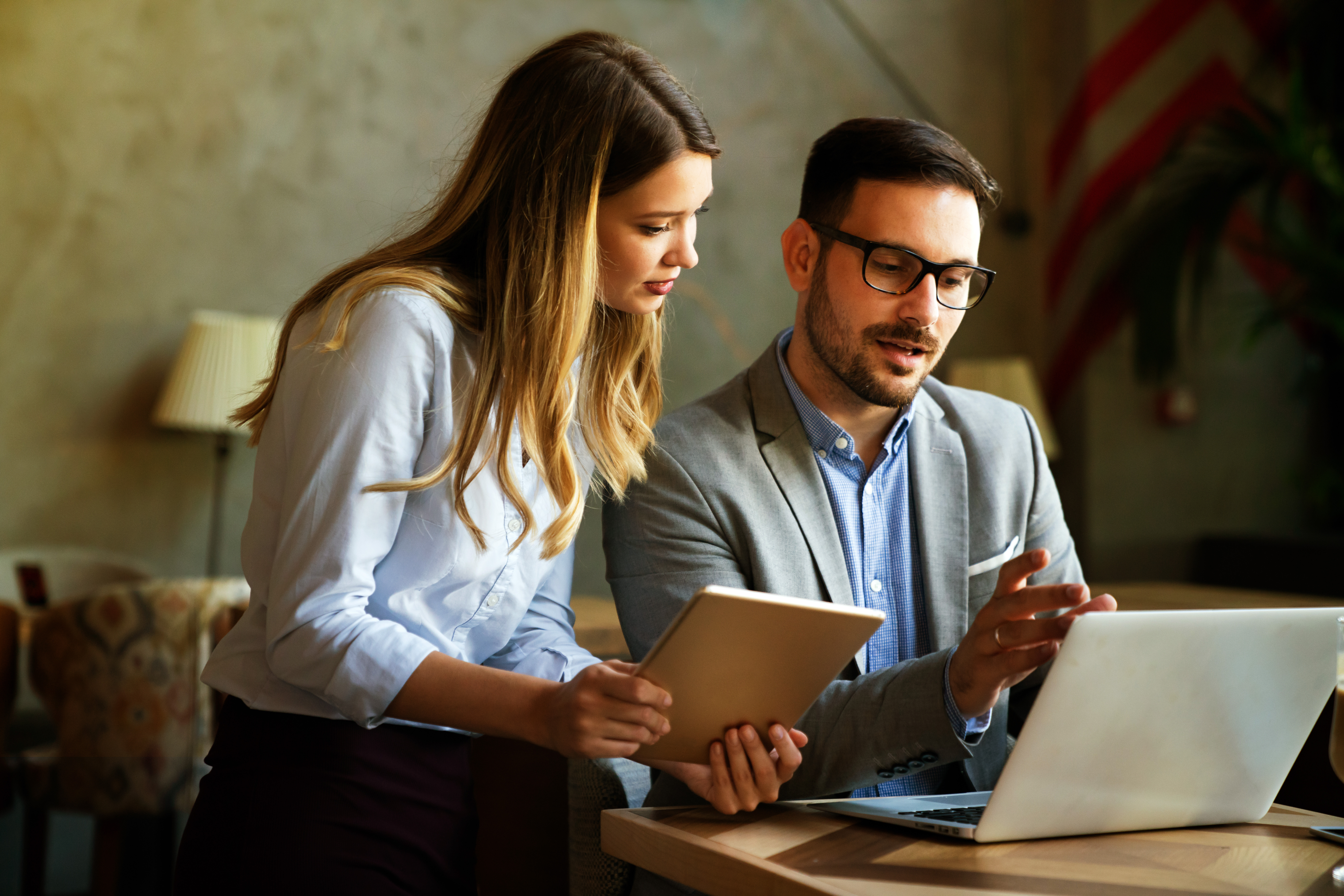 Two colleagues working together with a laptop and tablet.