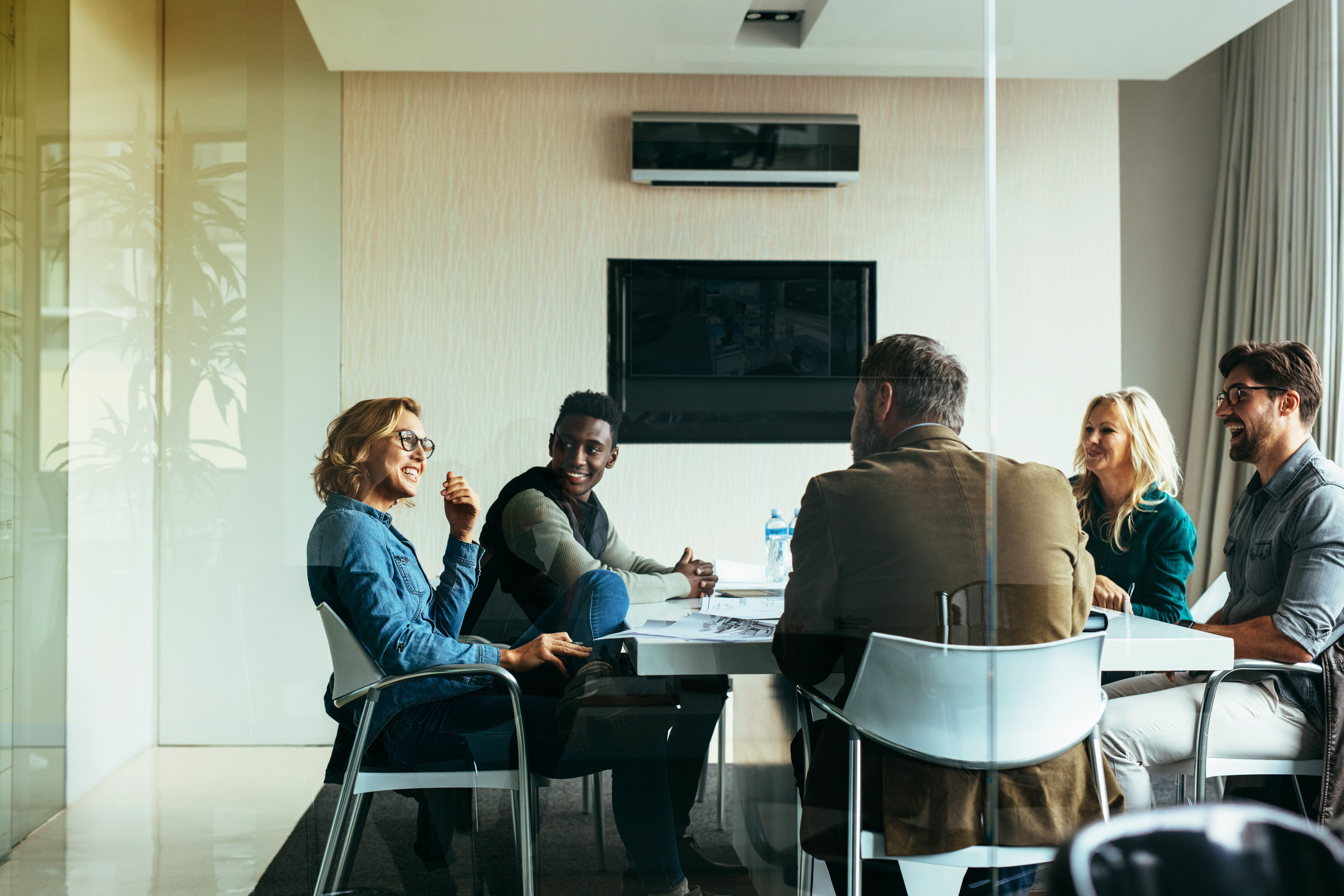 Group of professionals having a meeting in a glass-walled conference room.