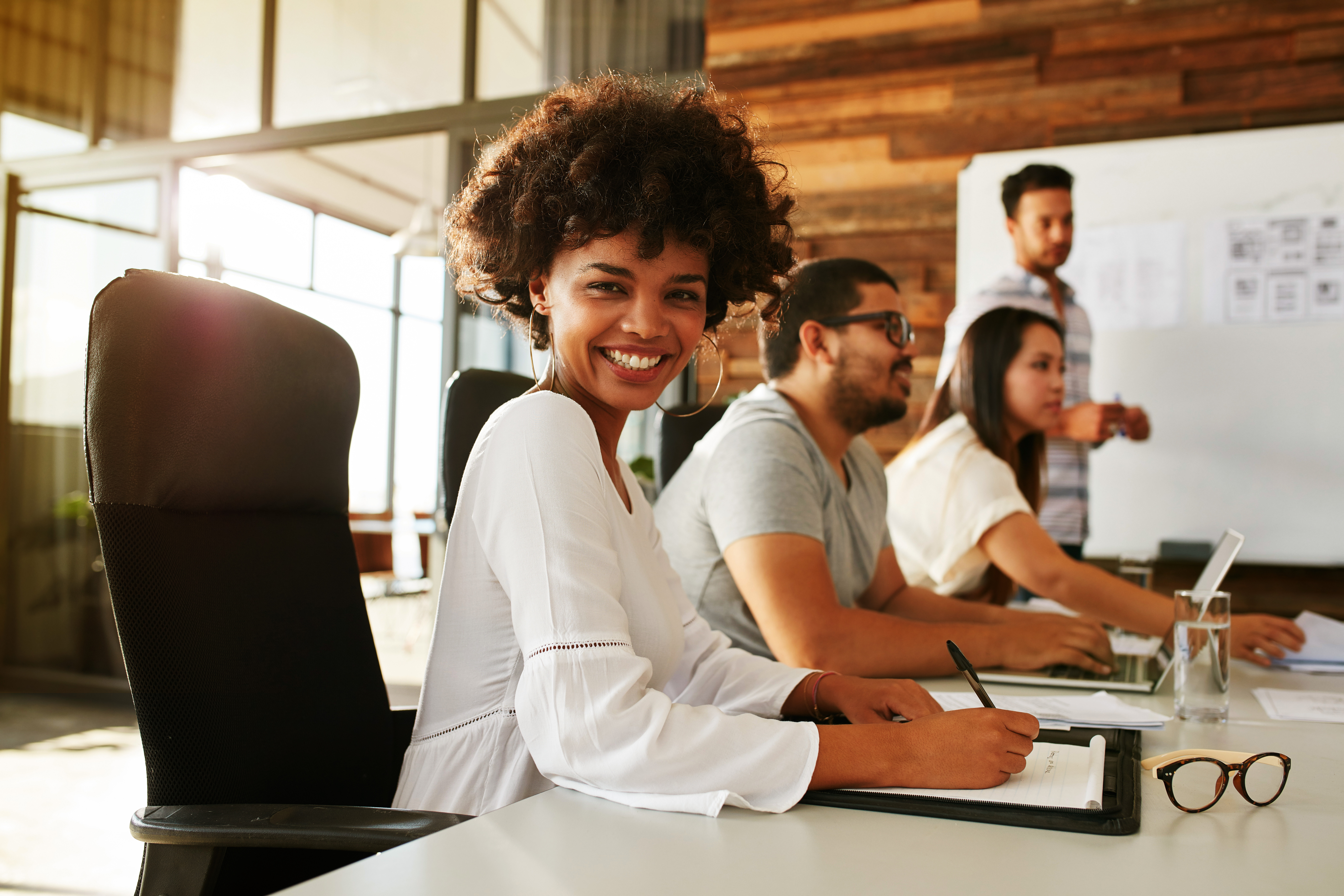Group of diverse people working together at a desk in a bright, modern office environment.