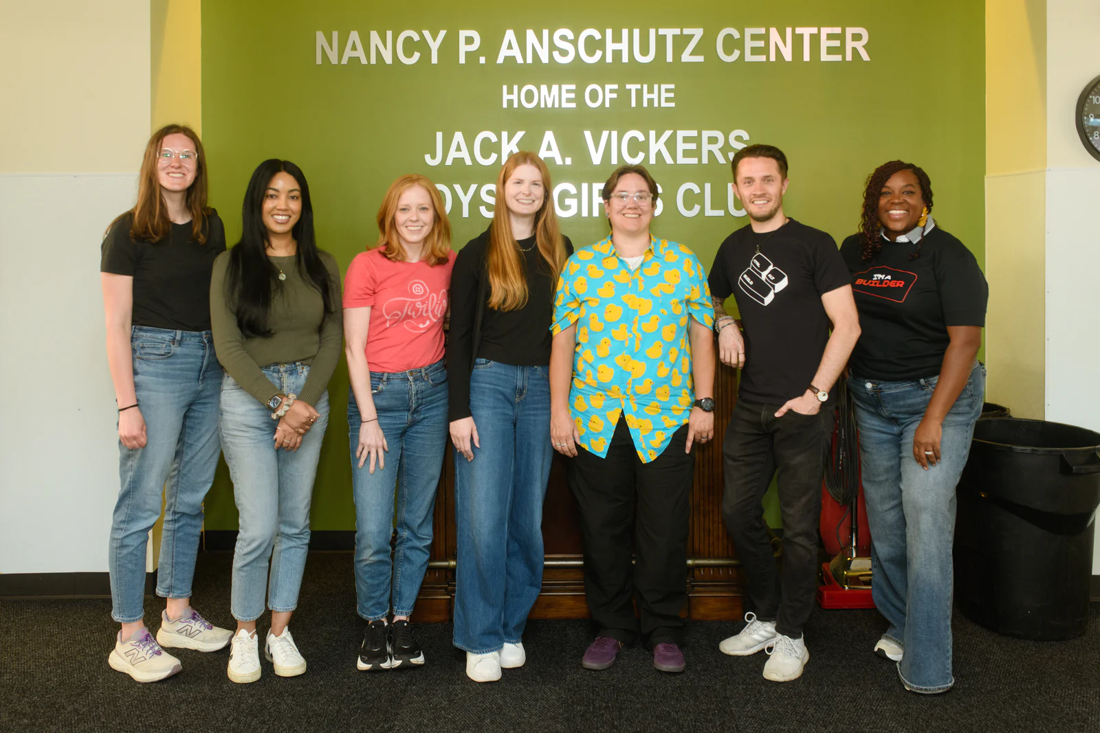 Group of Young Adults Standing Together at Nancy P. Anschutz Center Seven people standing in front of the Nancy P. Anschutz Center sign, smiling at the camera.