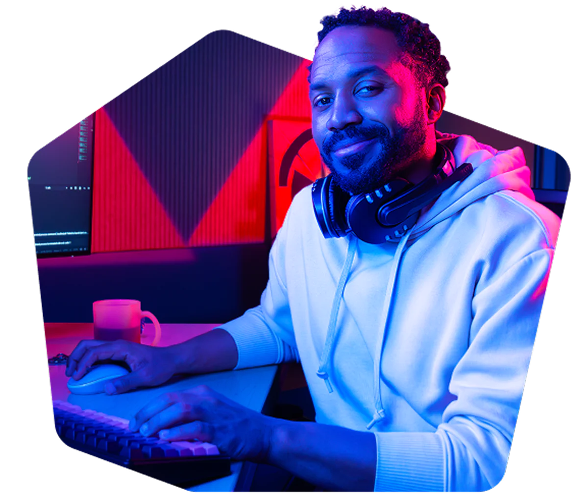Man wearing headphones, sitting in front of a computer, in a room with blue and red lighting.
