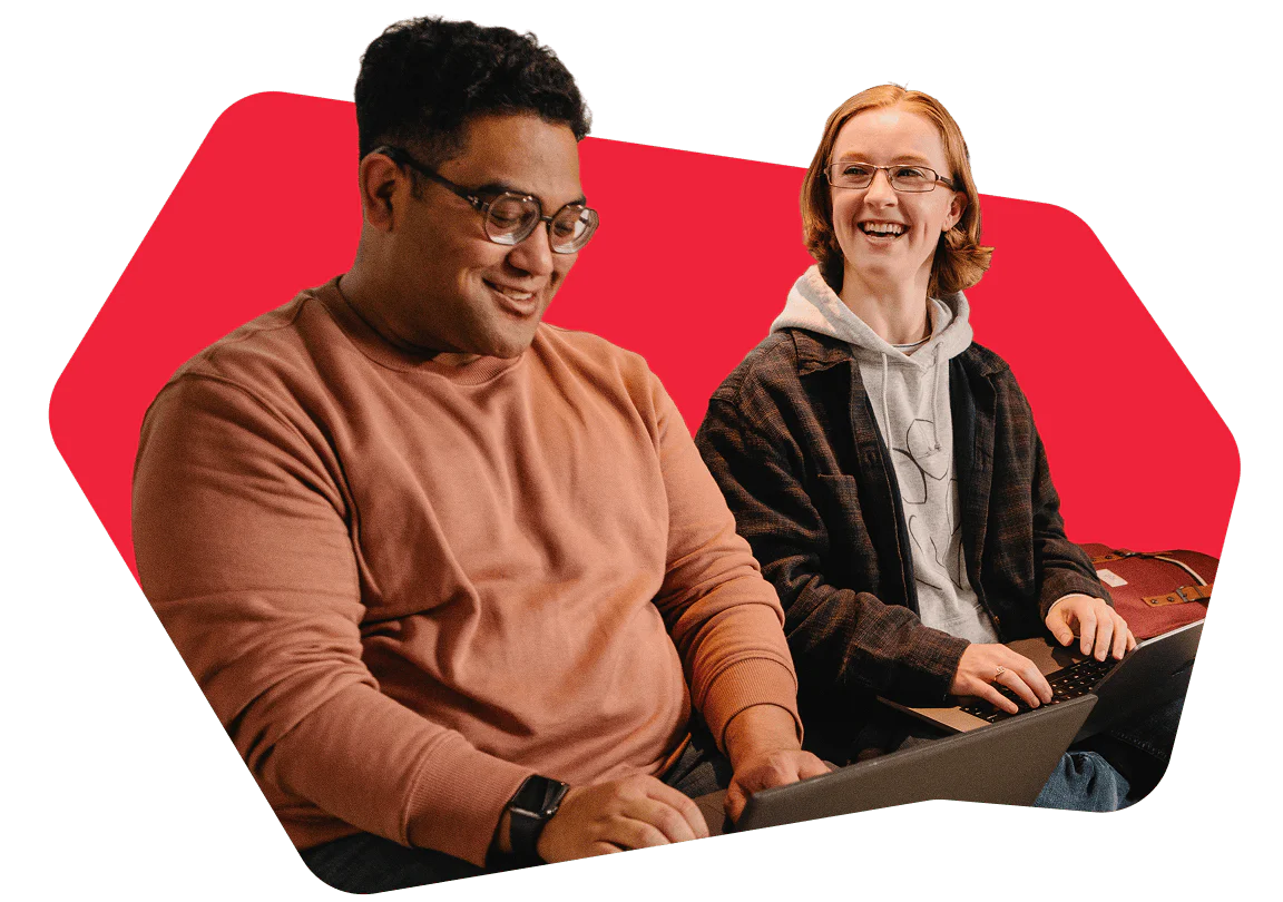 Two people smiling and working on laptops.