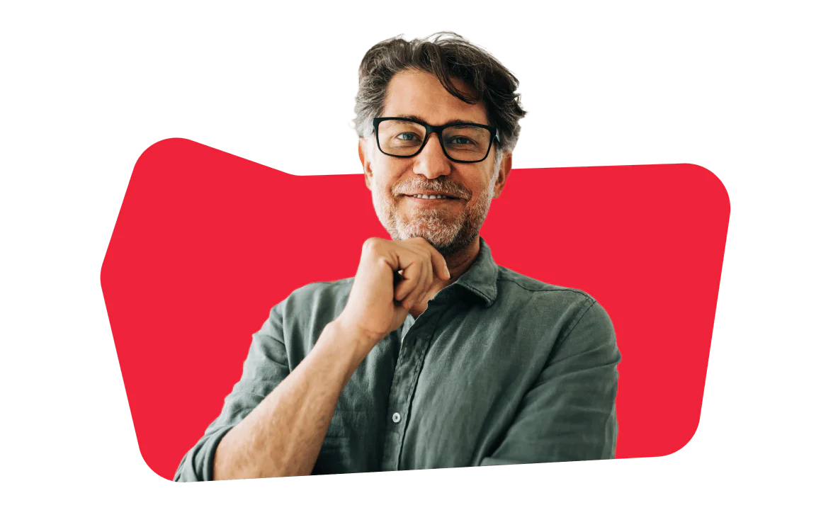 Man wearing glasses and a gray shirt smiling in front of a red background.