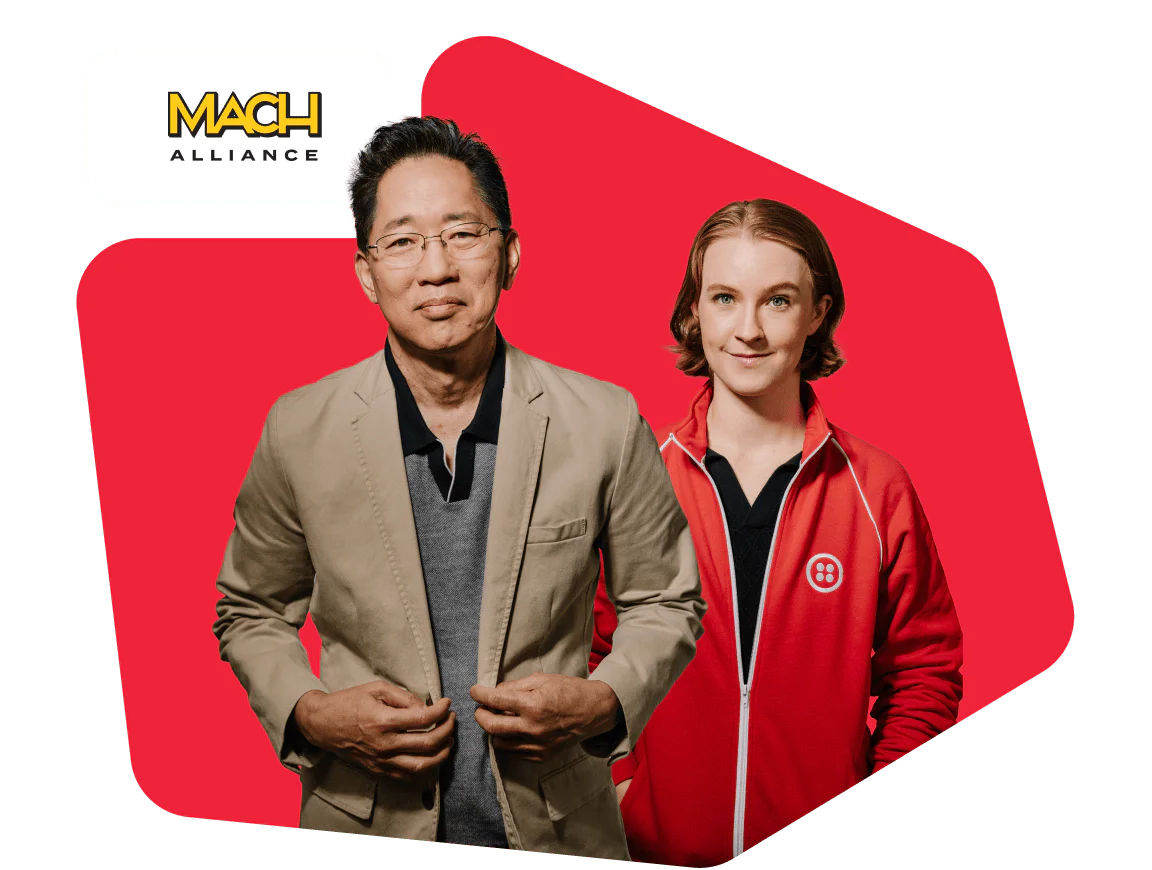 A man in a beige blazer and a woman in a red jacket representing MACH Alliance.