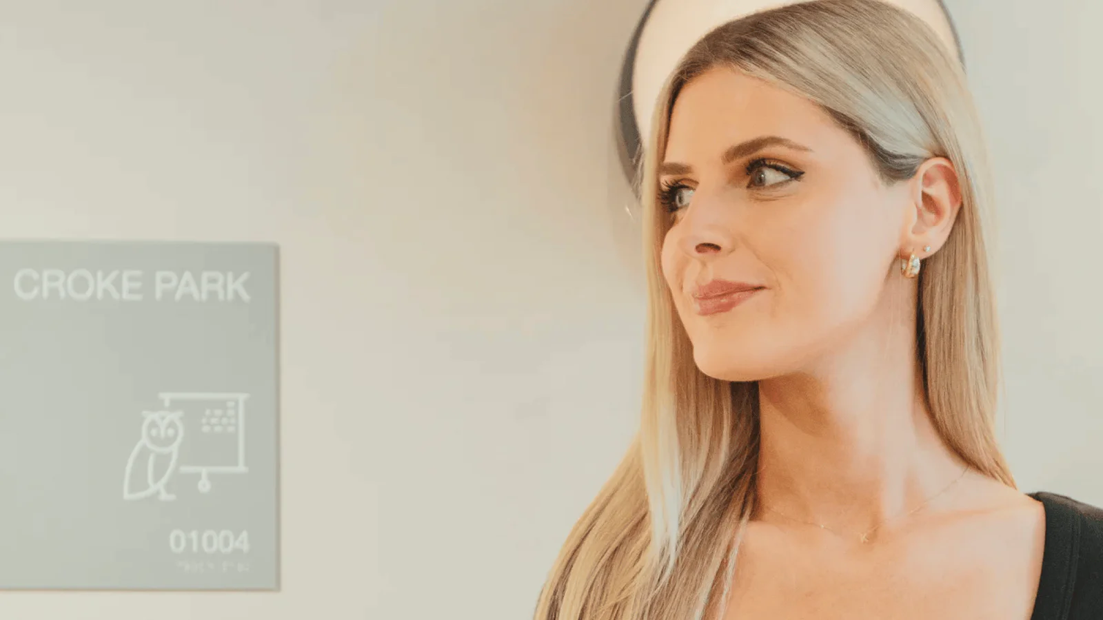 Woman with blonde hair standing beside a sign for Croke Park meeting room 01004